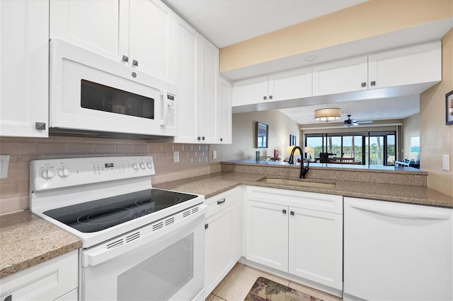 kitchen with white appliances, white cabinetry, backsplash, sink, and ceiling fan