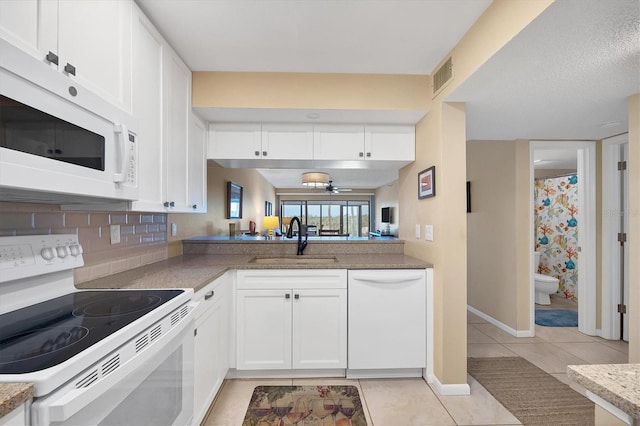 kitchen with white appliances, light tile flooring, tasteful backsplash, white cabinets, and sink