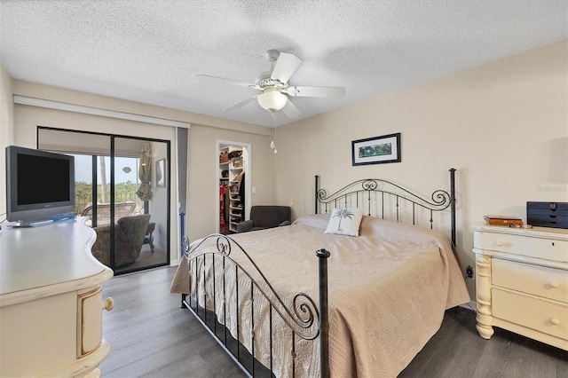 bedroom with a spacious closet, ceiling fan, access to exterior, and dark wood-type flooring