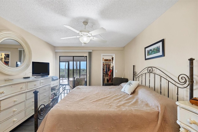 bedroom with a closet, access to exterior, a walk in closet, ceiling fan, and a textured ceiling