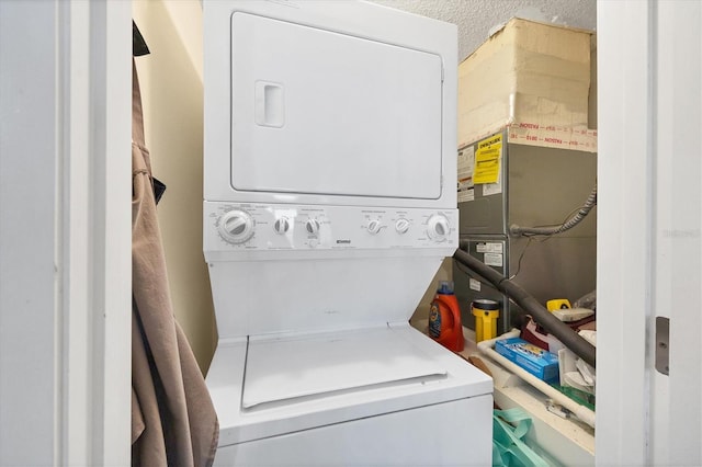 washroom with a textured ceiling and stacked washer / drying machine