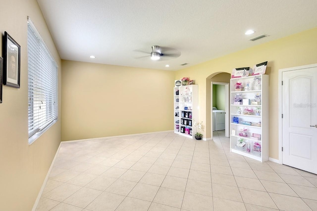 empty room featuring ceiling fan, light tile flooring, washer and clothes dryer, and a textured ceiling