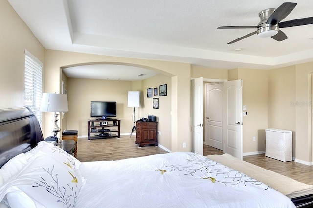 bedroom featuring ceiling fan, a tray ceiling, and dark hardwood / wood-style floors