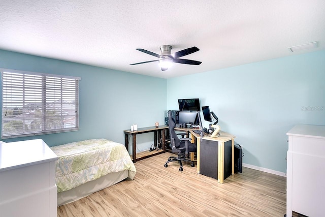 bedroom with light hardwood / wood-style flooring, ceiling fan, and a textured ceiling