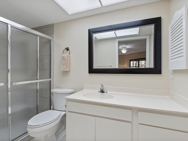 bathroom featuring ceiling fan, vanity, toilet, and a shower with shower door