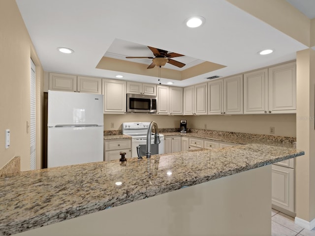 kitchen with white appliances, ceiling fan, a raised ceiling, and light stone counters