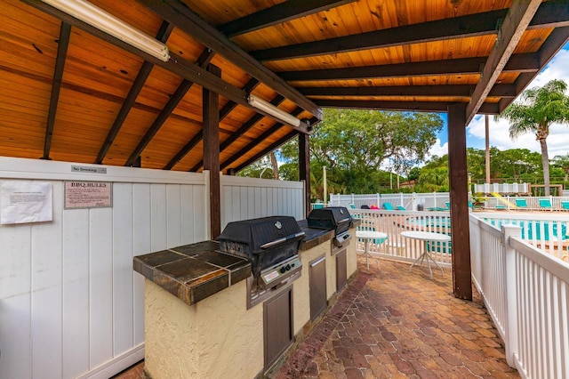 view of terrace with an outdoor kitchen, grilling area, and a community pool