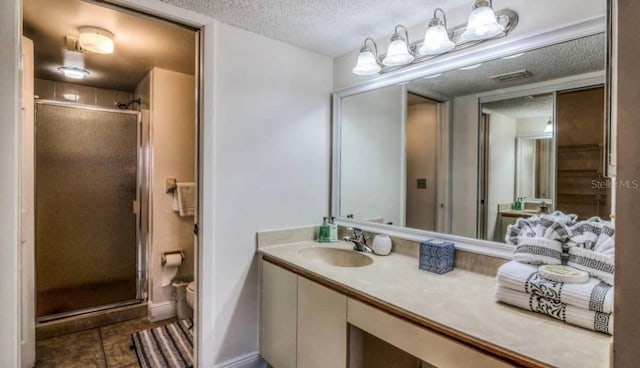 bathroom featuring a shower with door, tile floors, oversized vanity, and a textured ceiling