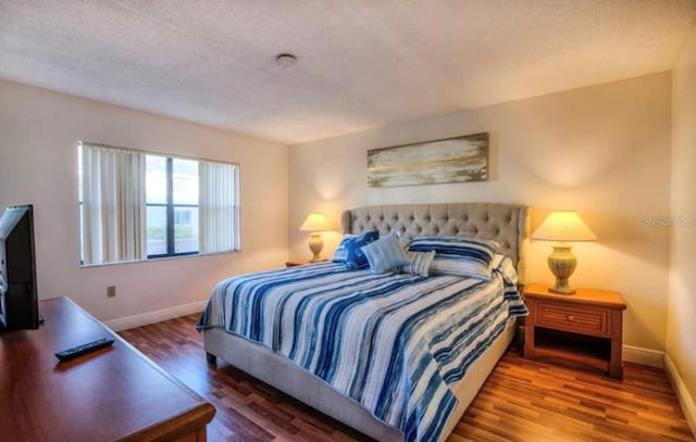 bedroom with a textured ceiling and dark hardwood / wood-style flooring