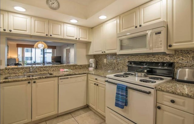 kitchen with white appliances, light stone countertops, light tile floors, sink, and tasteful backsplash