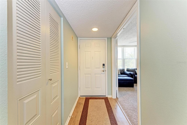 entryway featuring light colored carpet and a textured ceiling