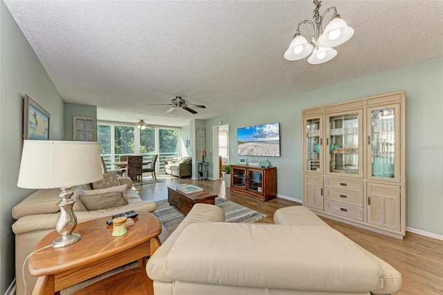 living room with ceiling fan with notable chandelier, light hardwood / wood-style floors, and a textured ceiling