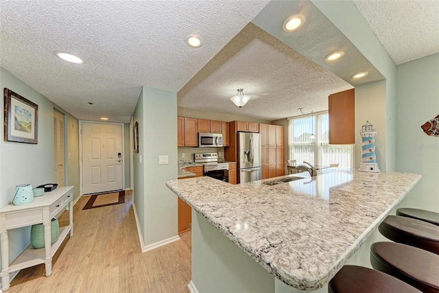 kitchen with kitchen peninsula, a textured ceiling, stainless steel appliances, and sink