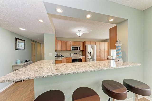 kitchen featuring a breakfast bar area, stainless steel appliances, and light wood-type flooring