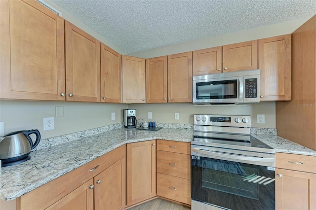 kitchen featuring stainless steel appliances, a textured ceiling, and light stone counters