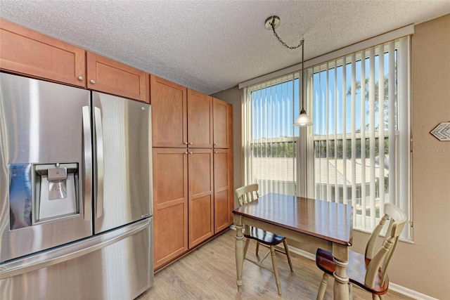 kitchen with stainless steel fridge with ice dispenser, a textured ceiling, a wealth of natural light, pendant lighting, and light wood-type flooring