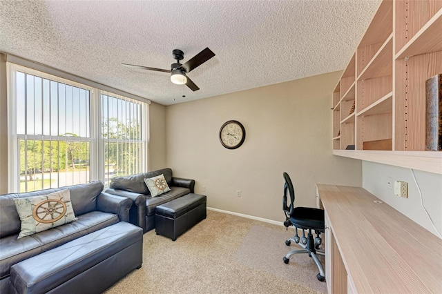 carpeted office space featuring ceiling fan and a textured ceiling