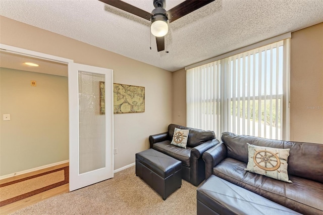 living room featuring light hardwood / wood-style floors, ceiling fan, and a textured ceiling