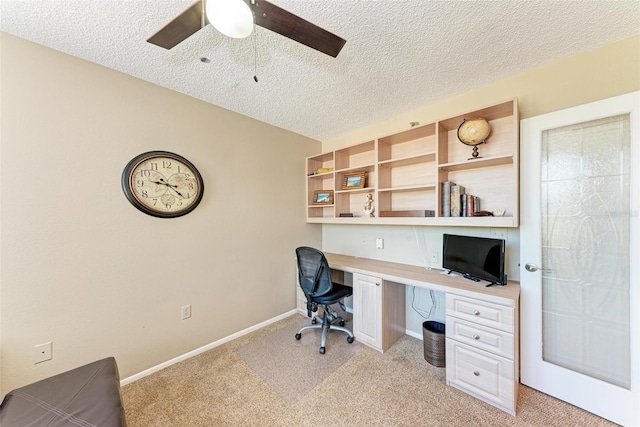 carpeted home office featuring ceiling fan, built in desk, and a textured ceiling