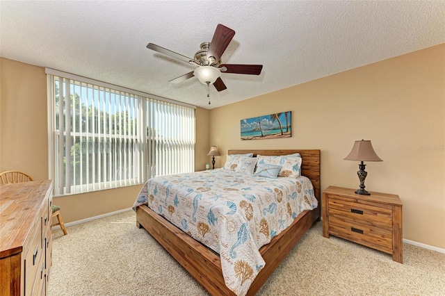 carpeted bedroom with ceiling fan and a textured ceiling