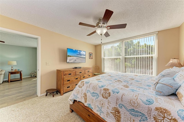 bedroom featuring ceiling fan, light wood-type flooring, and a textured ceiling