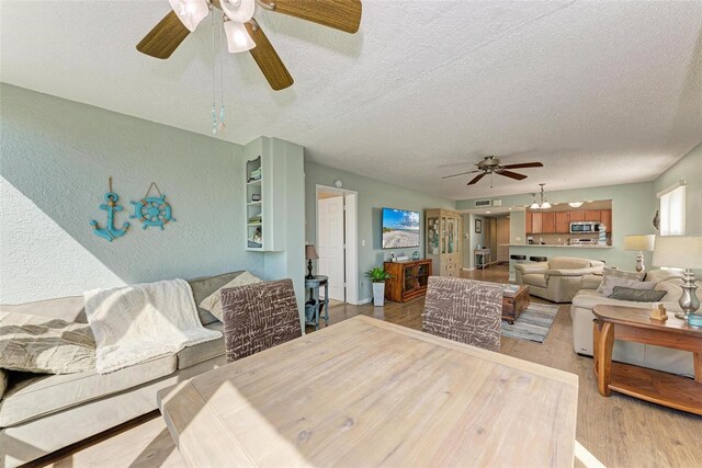 dining space with ceiling fan, light wood-type flooring, and a textured ceiling