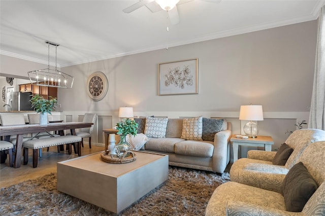 living room featuring ceiling fan with notable chandelier and ornamental molding