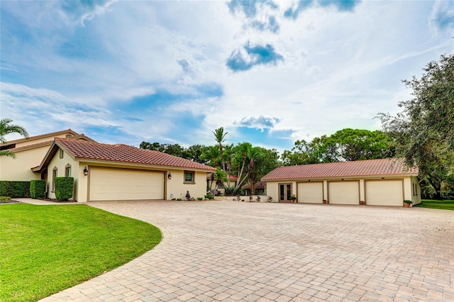 mediterranean / spanish-style home featuring a garage, a tile roof, a front yard, and stucco siding