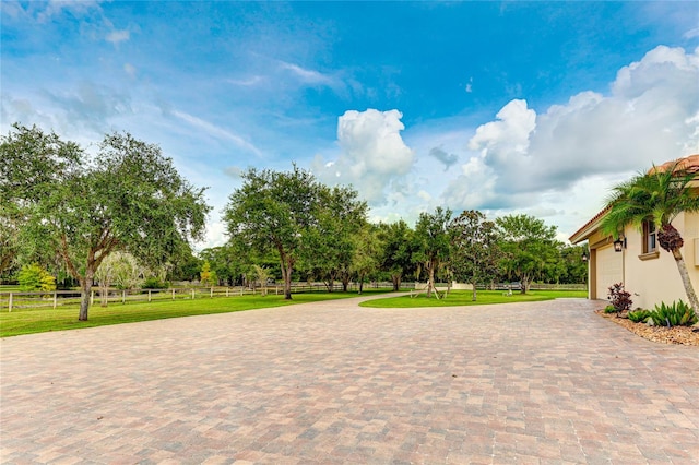 view of property's community featuring a garage, fence, decorative driveway, and a yard