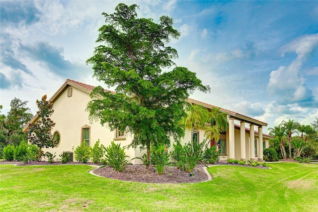 view of home's exterior featuring stucco siding, a tiled roof, and a yard