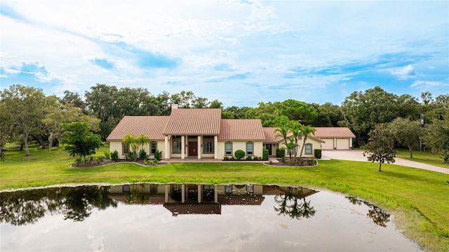 rear view of house featuring a tiled roof, a yard, a chimney, and a water view