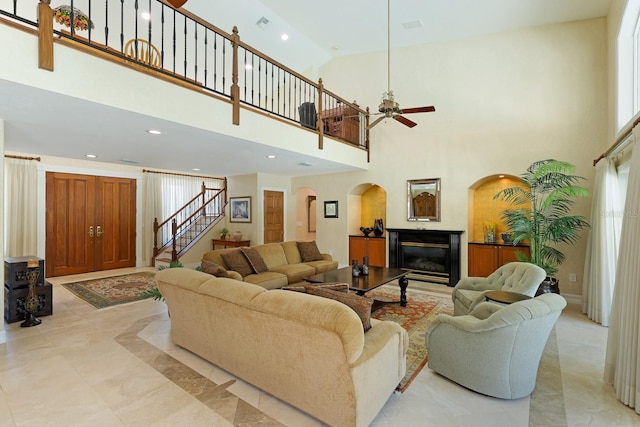 living room with arched walkways, recessed lighting, a ceiling fan, a glass covered fireplace, and stairs