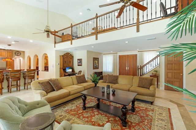 living room featuring arched walkways, recessed lighting, visible vents, a ceiling fan, and stairway