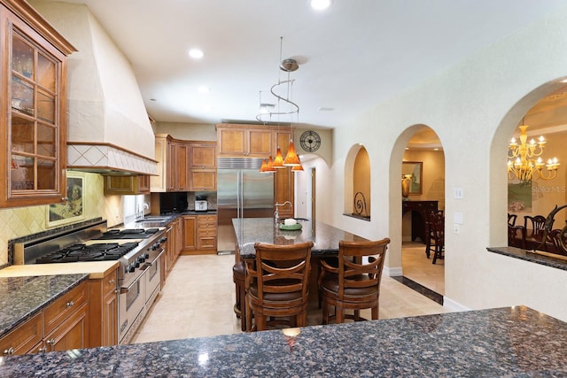 kitchen with tasteful backsplash, dark stone counters, custom range hood, high quality appliances, and a sink