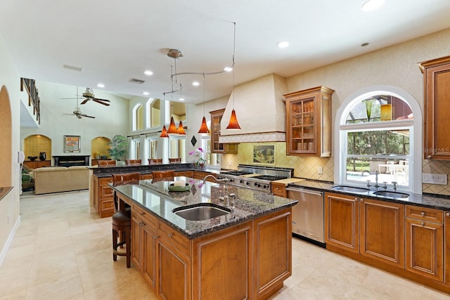 kitchen with brown cabinetry, premium range hood, a sink, and dishwasher