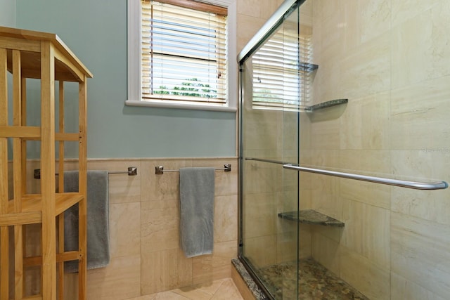 full bathroom with wainscoting, a shower stall, and tile walls