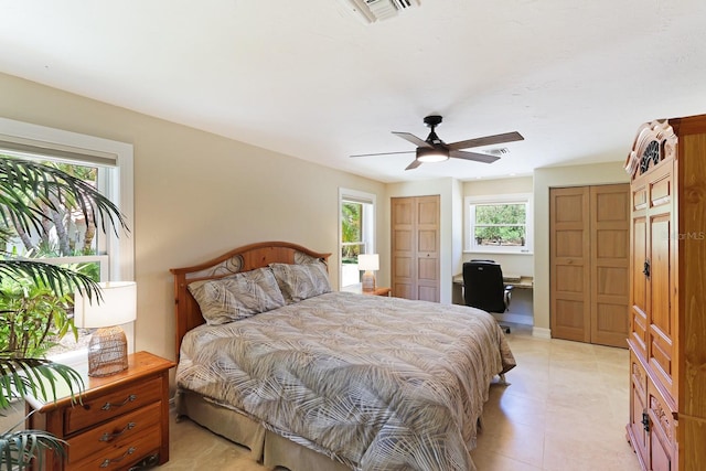 bedroom with built in study area, visible vents, and a ceiling fan