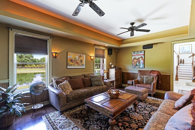 living room featuring a ceiling fan, a wainscoted wall, stairway, and wood finished floors