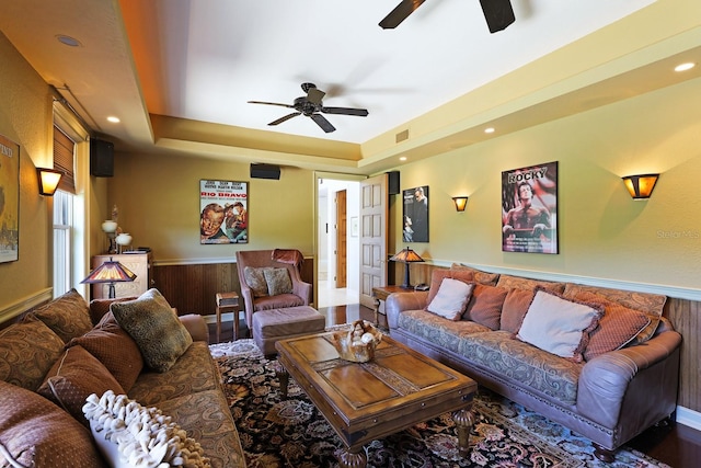 living room with ceiling fan, wainscoting, and a raised ceiling