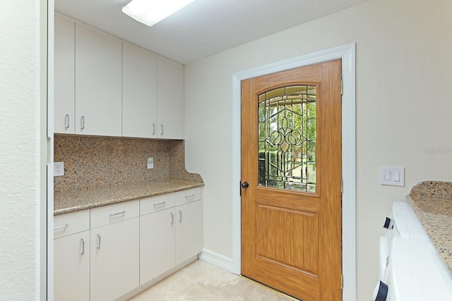 interior space featuring light stone counters, baseboards, white cabinets, and backsplash