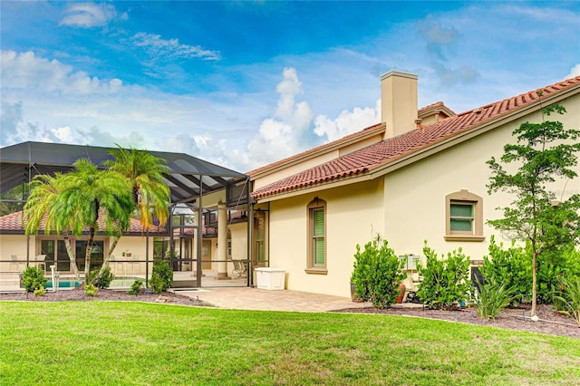 back of property featuring a yard, stucco siding, glass enclosure, a patio area, and a tiled roof