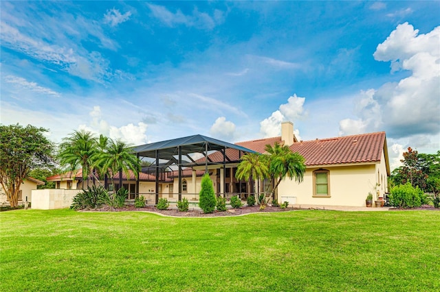 back of house featuring a chimney, a tiled roof, a lanai, a yard, and stucco siding