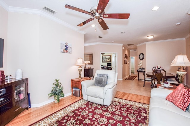 living room with ornamental molding, ceiling fan, and light wood-type flooring