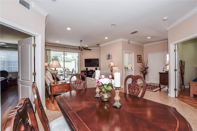 tiled dining space with ceiling fan and crown molding