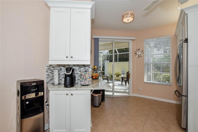 kitchen featuring white cabinets, stainless steel refrigerator, backsplash, and light tile floors