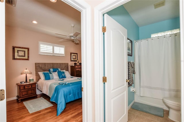 bedroom featuring connected bathroom, ceiling fan, and light tile floors