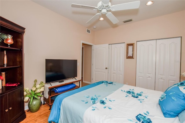 bedroom featuring multiple closets, ceiling fan, and light wood-type flooring