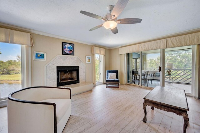 living room featuring crown molding, a premium fireplace, light hardwood / wood-style flooring, and a textured ceiling