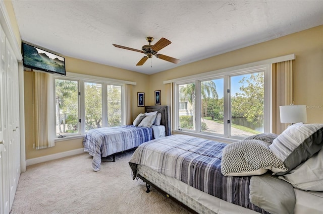 carpeted bedroom featuring multiple windows, a textured ceiling, and ceiling fan