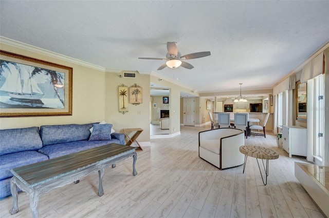 living room with crown molding, light hardwood / wood-style flooring, a textured ceiling, and ceiling fan